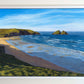Framed original oil painting by Naomi Jenkin depicting a bright spring morning at Holywell Bay, Cornwall, looking down from the cliff top towards Gull Rocks and Penhale, with lines of swell rolling into shore and footprints on the sand below