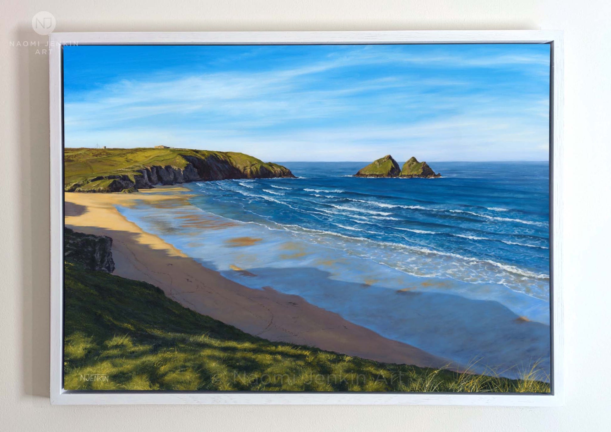 Framed original oil painting by Naomi Jenkin depicting a bright spring morning at Holywell Bay, Cornwall, looking down from the cliff top towards Gull Rocks and Penhale, with lines of swell rolling into shore and footprints on the sand below