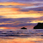 Original oil painting by Naomi Jenkin of a sunset at Polzeath Beach, Cornwall, with a vibrant sky of oranges, yellows and reds, purple clouds, and the inky silhouettes of Pentire Point and Newlands Rock.